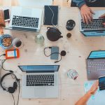 Draufsicht eines Teams, das an Laptops, Smartphones und Dokumenten zusammenarbeitet. erecruiter, Bewerbermanagement