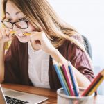 Frustrierte Frau beißt auf Bleistift und arbeitet am Laptop. erecruiter, Bewerbermanagement
