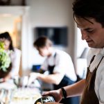 Koch bereitet mit Kollegen Essen in einer Restaurantküche zu erecruiter, Bewerbermanagement