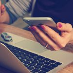 Frau nutzt Smartphone und Laptop und arbeitet von zu Hause aus. erecruiter, Bewerbermanagement