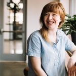 Lächelnde Frau sitzt in der Nähe eines Fensters, erfolgreiches Kandidatenprofil erecruiter, Bewerbermanagement