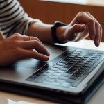 Person verwendet Laptop, Hände auf Tastatur und Trackpad. erecruiter, Bewerbermanagement