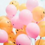 Rosa und orangefarbene Luftballons mit glücklichen und traurigen Gesichtern veranschaulichen die psychische Gesundheit am Arbeitsplatz. erecruiter, Bewerbermanagement