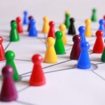 Bunte Spielsteine in einem Netzwerk, die Führung auf Distanz und Vertrauen veranschaulichen. erecruiter, Bewerbermanagement