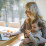 Frau arbeitet mit Baby am Laptop und balanciert Vereinbarkeit von Familie und Beruf; Flexible Arbeitszeiten verbinden Familienalltag und Beruf - eRecruiter